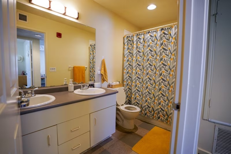 Bost Hall bathroom that includes a double sink, toilet, and tub/shower