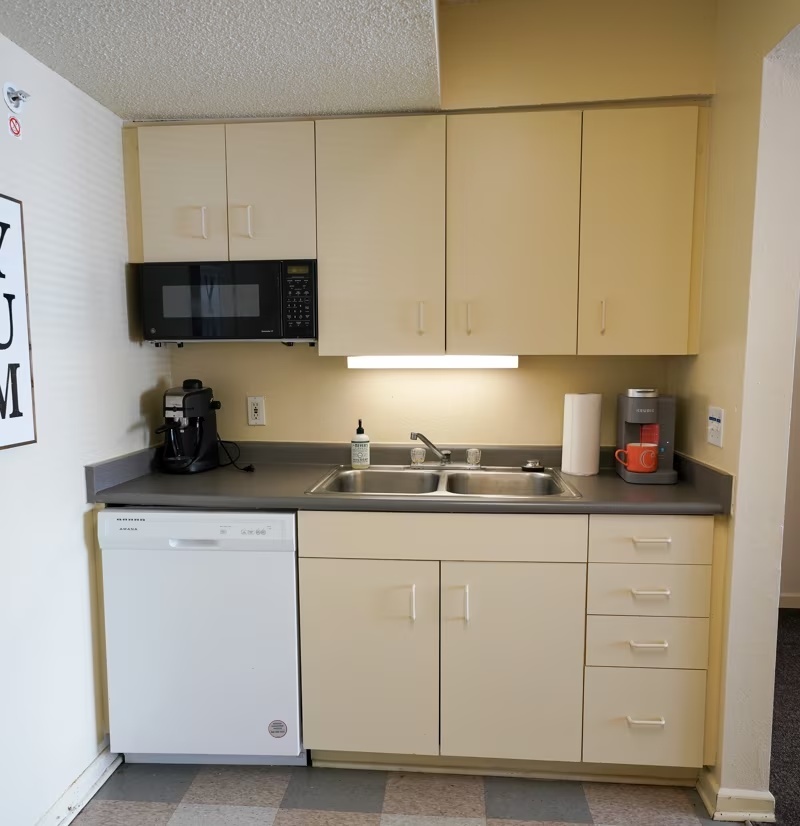 Bost Hall kitchenette: beige cabinetry over a short countertop space