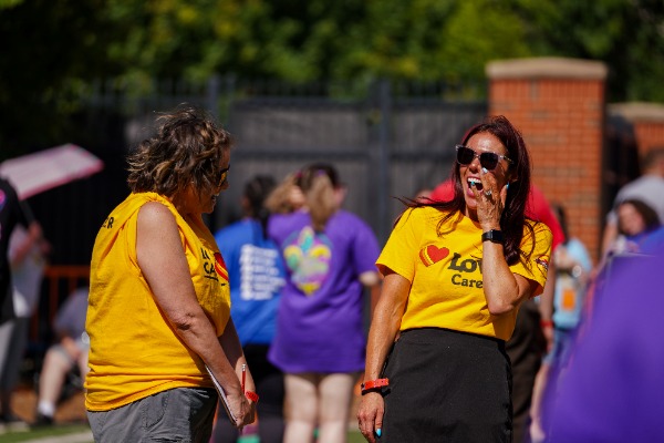 Two women laughing and talking with eachother while volunteering at Special Olympics. 