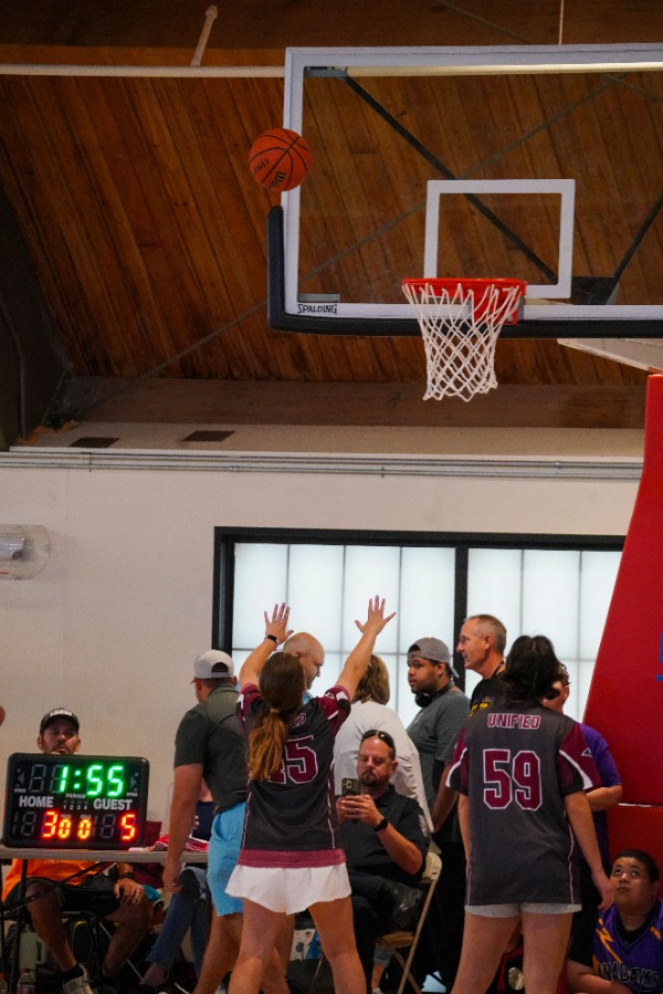 Girl shooting basketball at Special Olympics basketball match.