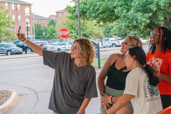 Students pose for group selfie in front of dorm during scavenger hunt
